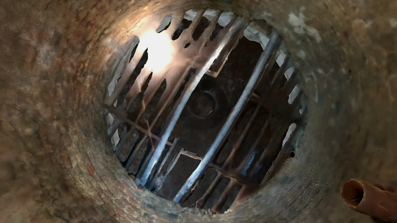 The iron grate at the top of the well, seen from below inside the shaft